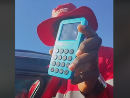 A car guard holds a card machine at a car door