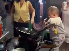 A Chinese baby cooks with a wok on street