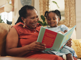 A grandmother reads a book with her granddaughter
