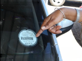 A lady pointing to a car licence disc