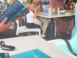 A little girl sitting at another family's table