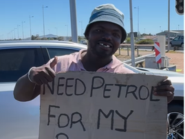 A man holding a placard at the traffic lights begging