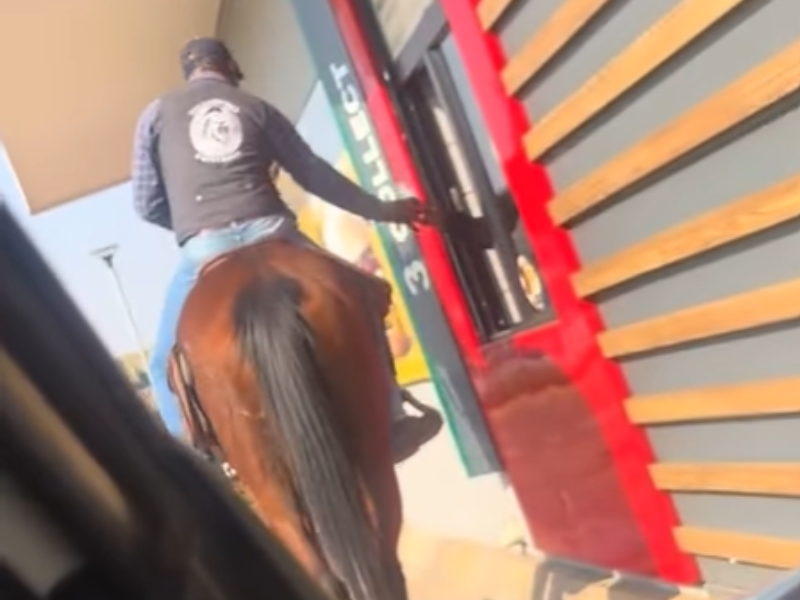 A man on a horse at a McDonalds drive thru