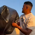 A man tries to capture smoke from a braai with a black refuse bag