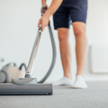 A man wearing shorts vacuuming the floor