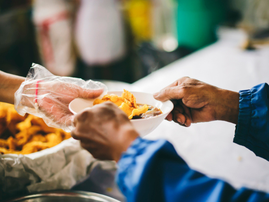 A person giving another person warm bowl of food