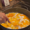 A person smashes eggs in a frying pan on the stove top