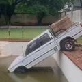 A van is halfway inside a pool