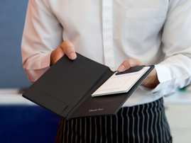 A waiter holds a the bill for customer out