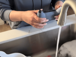 A woman washes a gaming controller under tap water