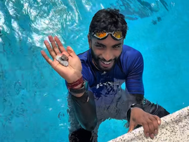 A young guy swimming holding out a hand full of change