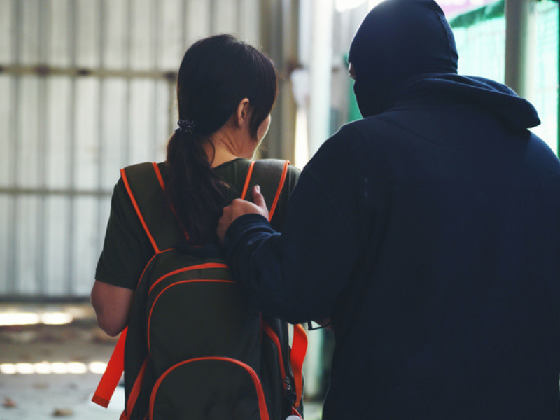 An armed man kidnapping a girl with a backpack