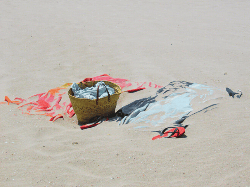 Beach towel and other belongings messed with beach sand at the beach