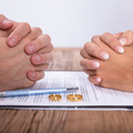 Couple's hands on divorce papers with gold wedding band rings