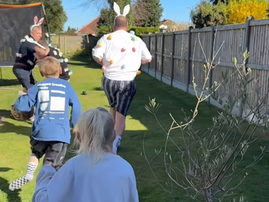 Kids run after their dads in the garden for an Easter egg hunt