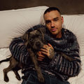 Liam Payne cuddling a dog on a white sofa