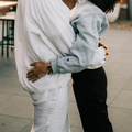 Man wearing white jacker holding a woman wearing a blue jacket