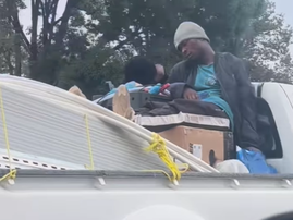 Two workers napping at the back of a moving bakkie