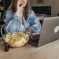 Woman eating chips and using a laptop