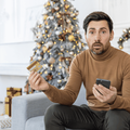 worried young man holding a credit card and phone